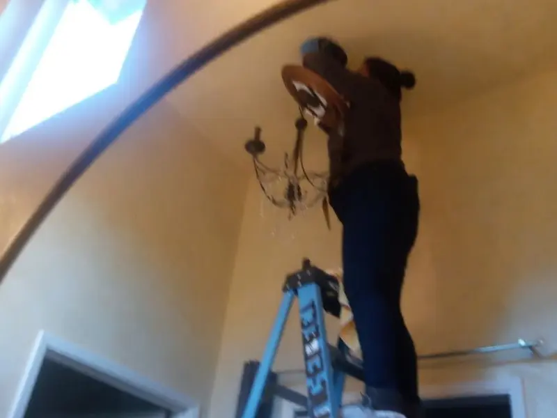 Electrician installing a chandelier in a Crockery residence